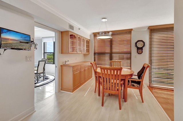 dining room with ornamental molding and light wood-type flooring