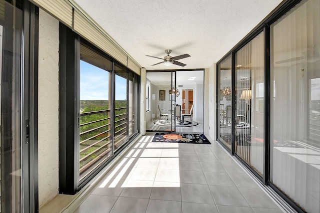 unfurnished sunroom with ceiling fan with notable chandelier