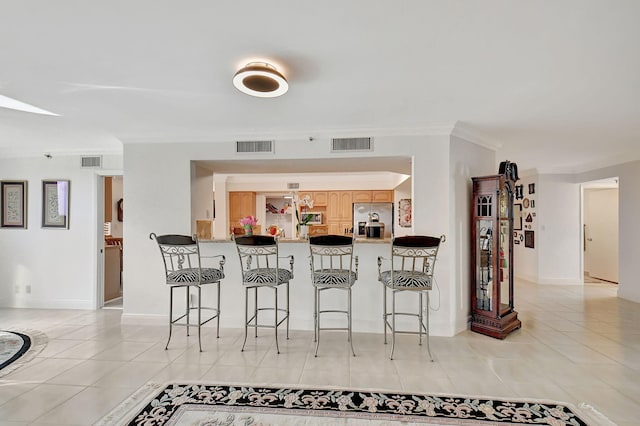 kitchen with a barn door, appliances with stainless steel finishes, crown molding, kitchen peninsula, and light tile patterned floors