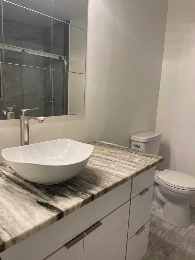 bathroom with walk in shower, vanity, toilet, and hardwood / wood-style flooring