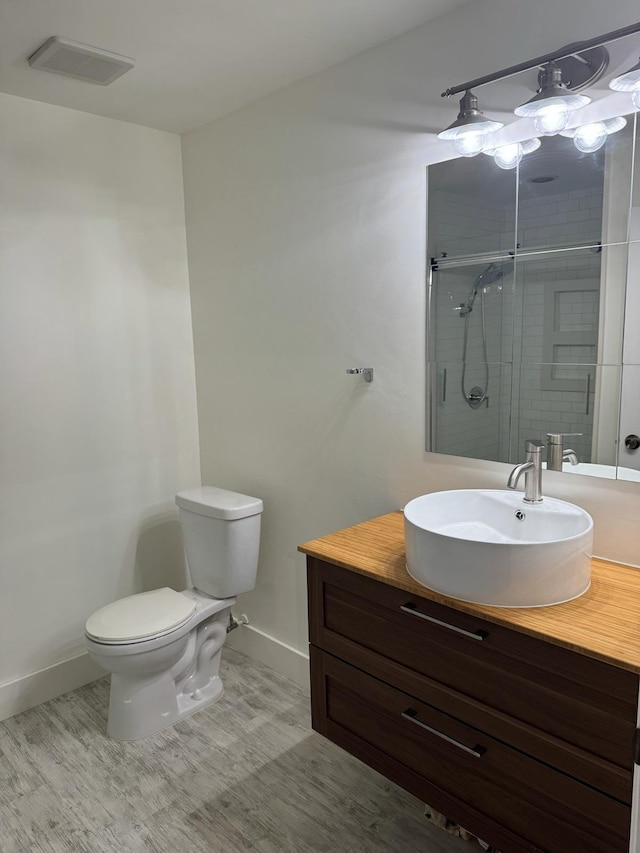 bathroom featuring an enclosed shower, wood-type flooring, toilet, and vanity