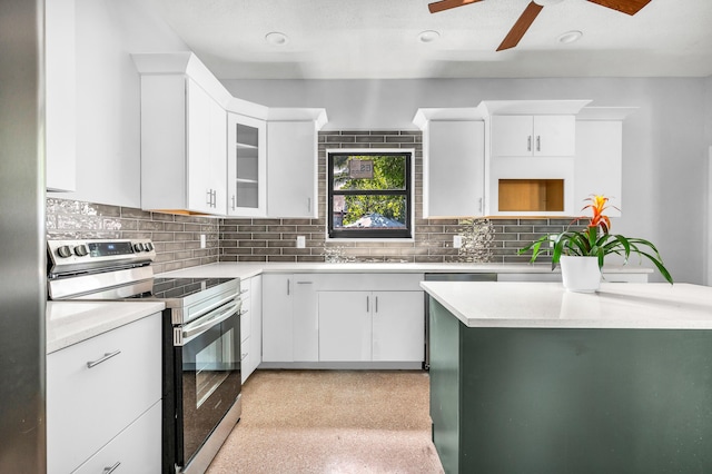 kitchen with stainless steel electric stove, backsplash, white cabinetry, and ceiling fan