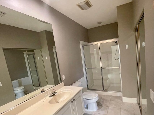 bathroom featuring tile patterned floors, a shower with door, vanity, and toilet