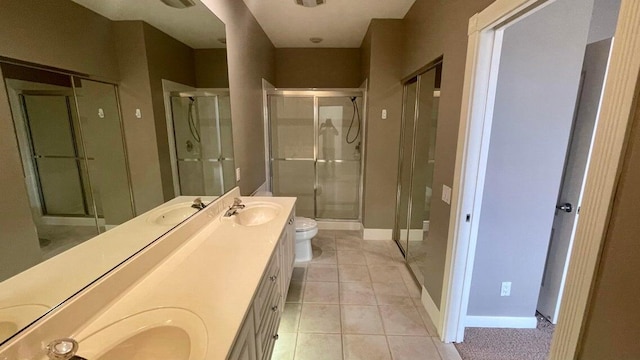 bathroom with tile patterned floors, vanity, toilet, and a shower with shower door