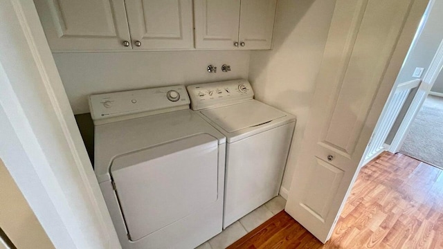 washroom with washer and clothes dryer, cabinets, and wood-type flooring