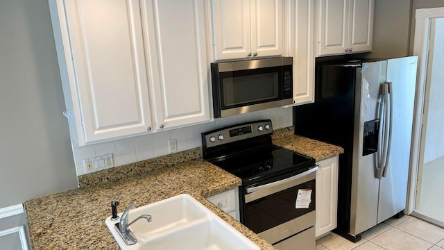 kitchen with appliances with stainless steel finishes, tasteful backsplash, light stone counters, sink, and white cabinetry