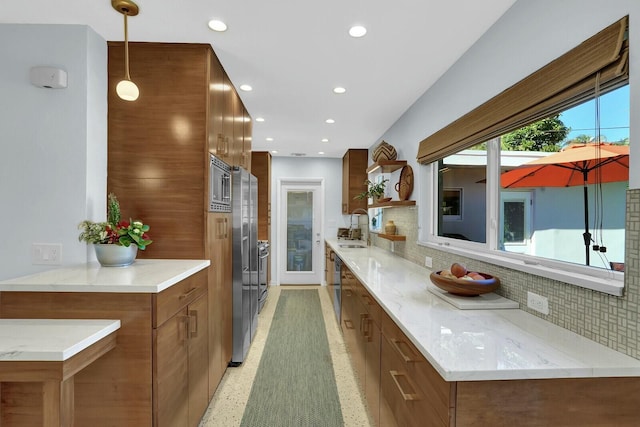 kitchen with decorative backsplash, sink, light stone counters, and decorative light fixtures