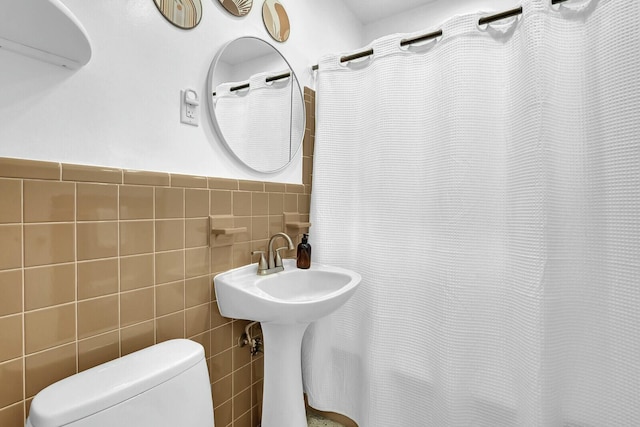 bathroom featuring toilet and tile walls