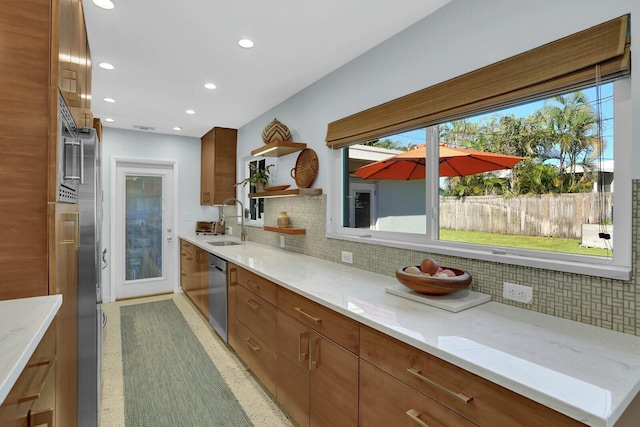 kitchen with tasteful backsplash, light stone countertops, dishwasher, and sink