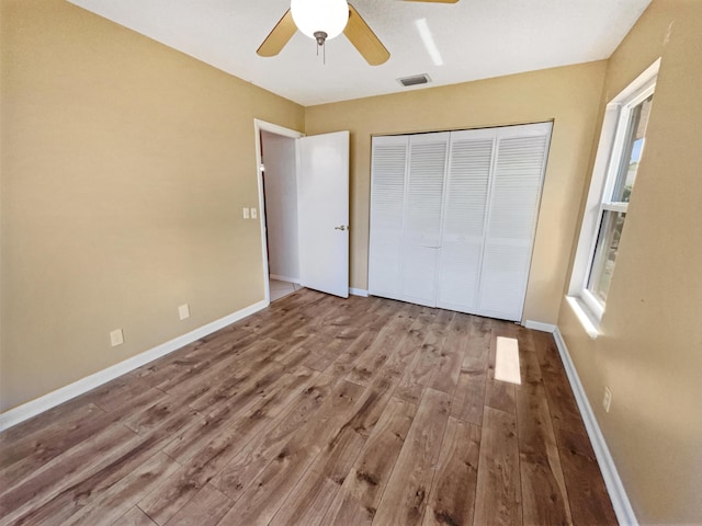 unfurnished bedroom with ceiling fan, light wood-type flooring, and a closet