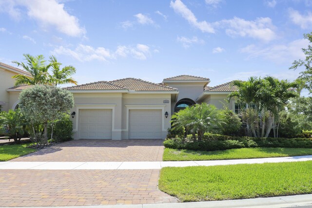 mediterranean / spanish-style house featuring a garage and a front lawn