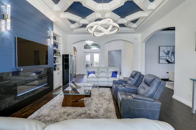 living room with coffered ceiling, crown molding, dark hardwood / wood-style floors, built in features, and a notable chandelier