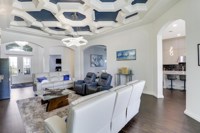 living room with coffered ceiling, dark wood-type flooring, french doors, and a chandelier