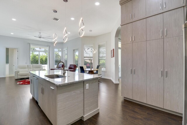 kitchen with sink, light brown cabinets, light stone countertops, and a center island with sink