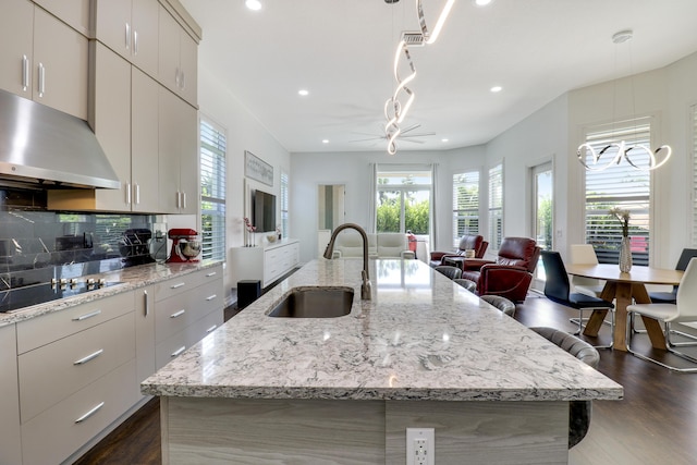 kitchen featuring sink, decorative backsplash, black electric cooktop, and a large island