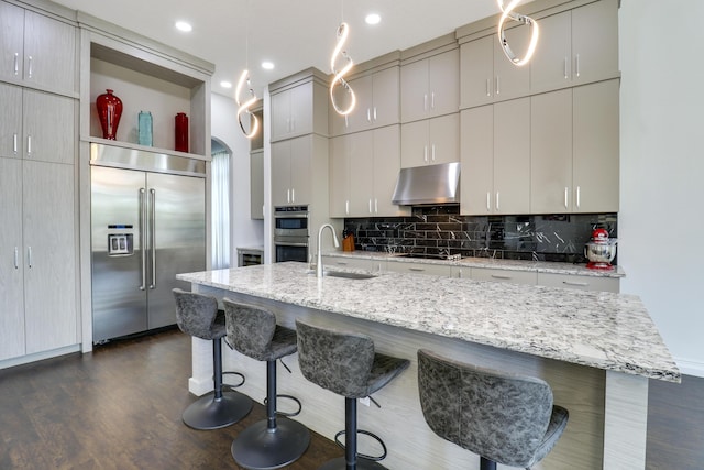 kitchen featuring sink, stainless steel appliances, an island with sink, a kitchen bar, and decorative backsplash