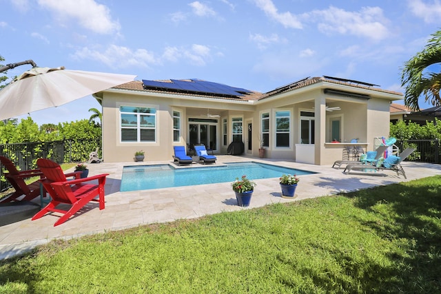 rear view of house featuring a fenced in pool, a lawn, ceiling fan, a patio, and solar panels