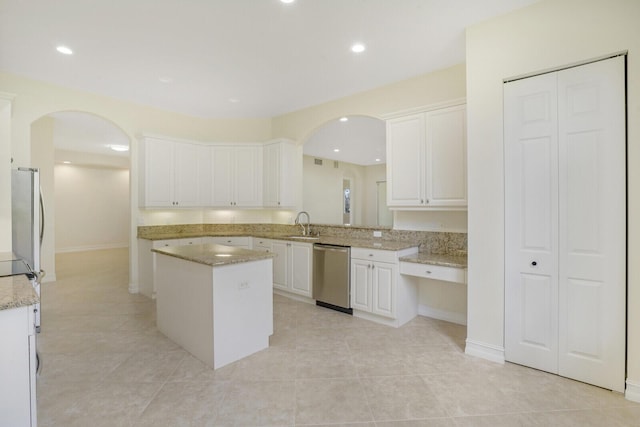 kitchen with sink, stainless steel appliances, light tile patterned floors, a kitchen island, and white cabinets