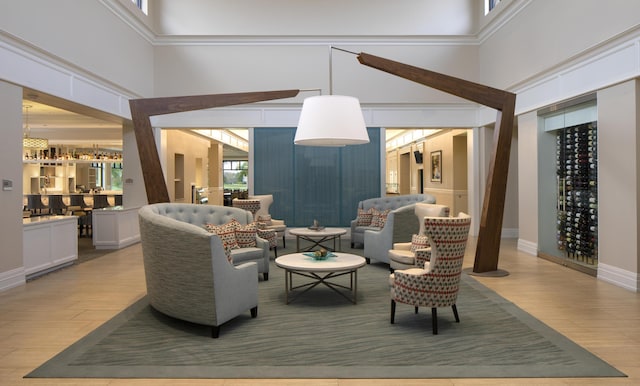 living room with hardwood / wood-style flooring, crown molding, and a high ceiling