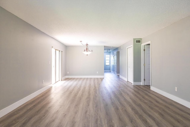 spare room featuring a textured ceiling and dark hardwood / wood-style flooring