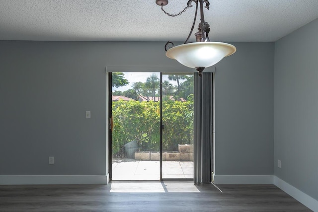 unfurnished dining area with dark hardwood / wood-style floors and a textured ceiling