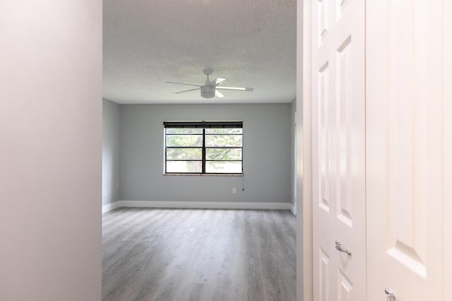 empty room featuring ceiling fan, wood-type flooring, and a textured ceiling