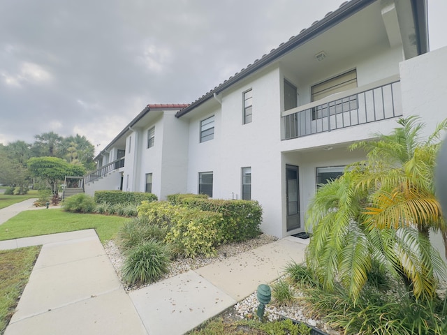 view of property exterior featuring a balcony and a lawn