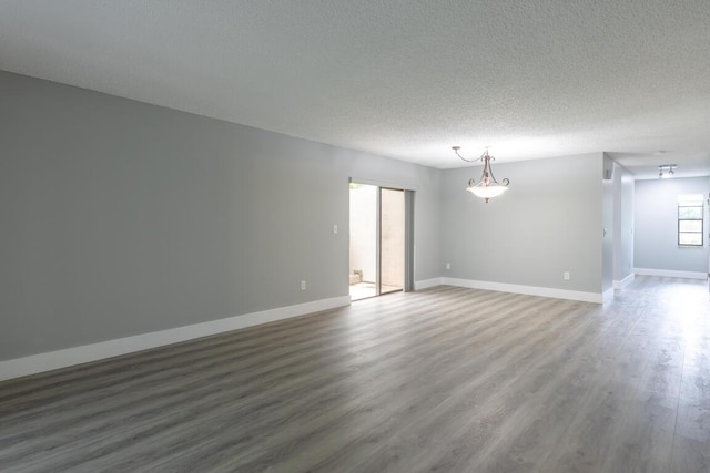 unfurnished room with a textured ceiling and dark hardwood / wood-style floors