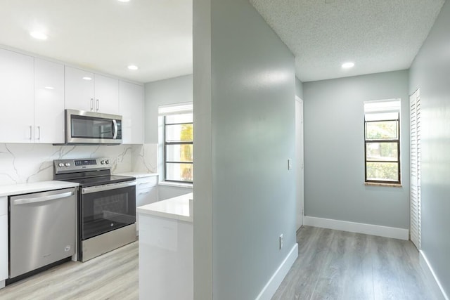 kitchen featuring plenty of natural light, white cabinets, stainless steel appliances, and light wood-type flooring