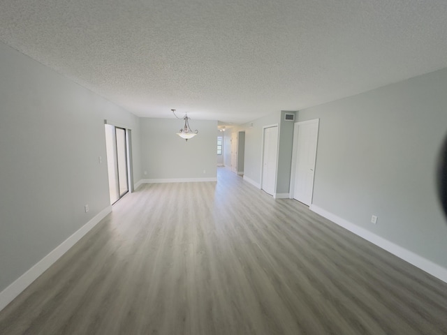 empty room with hardwood / wood-style floors and a textured ceiling