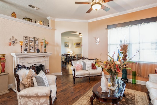 living room with a textured ceiling, ceiling fan, crown molding, and dark wood-type flooring