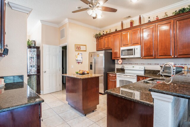 kitchen with white appliances, dark stone counters, and ceiling fan