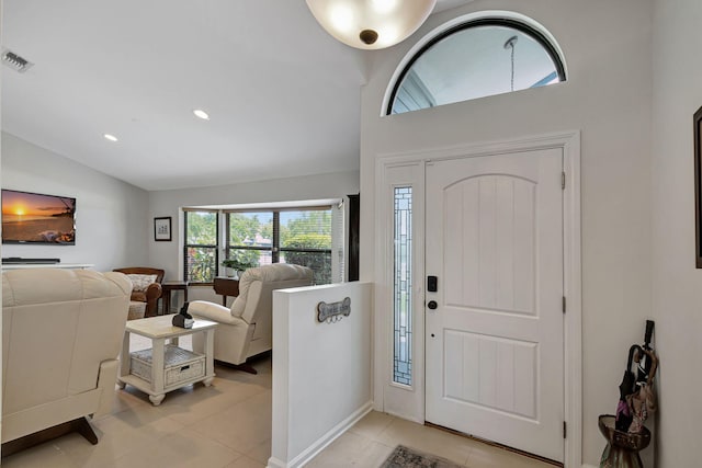 foyer entrance with light tile patterned floors and vaulted ceiling