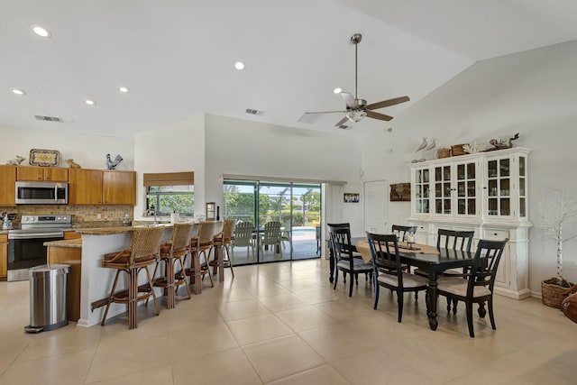 dining room featuring ceiling fan, light tile patterned floors, and high vaulted ceiling