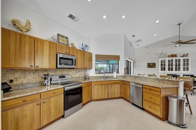 kitchen with ceiling fan, sink, light stone countertops, stainless steel appliances, and high vaulted ceiling