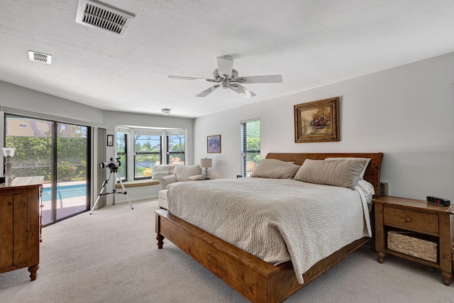 carpeted bedroom featuring access to outside, ceiling fan, and a textured ceiling