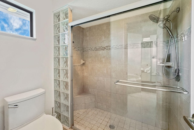 bathroom featuring toilet, a textured ceiling, and a shower with shower door