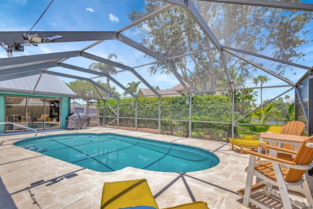 view of pool featuring grilling area, glass enclosure, and a patio