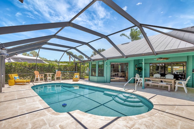 view of swimming pool with ceiling fan, glass enclosure, and a patio