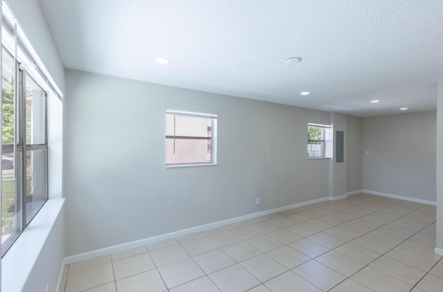 tiled spare room featuring a textured ceiling and electric panel