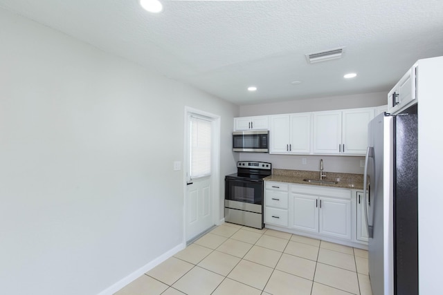 kitchen featuring white cabinets, sink, light tile patterned floors, light stone counters, and stainless steel appliances