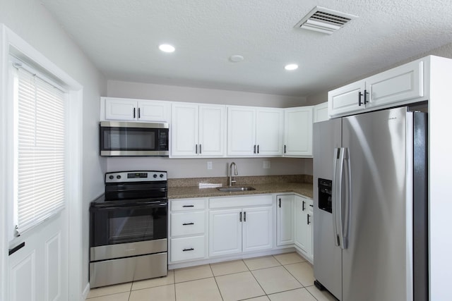 kitchen with white cabinetry, sink, light tile patterned floors, and stainless steel appliances