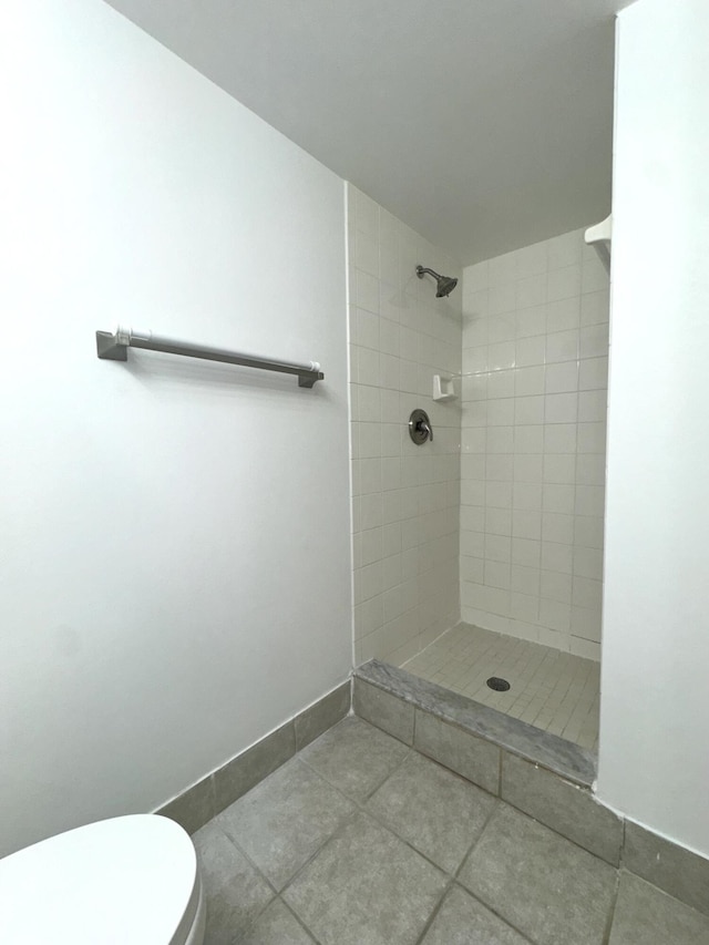 bathroom with a tile shower, tile patterned flooring, and toilet