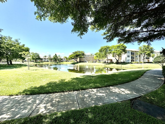 surrounding community with a water view and a yard