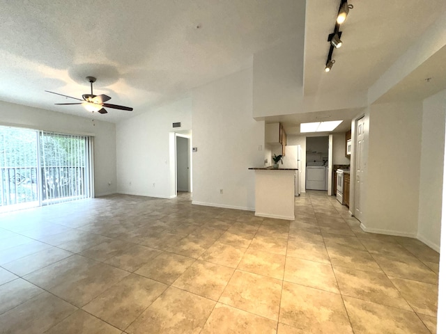 unfurnished living room with light tile patterned flooring, vaulted ceiling, a textured ceiling, track lighting, and ceiling fan