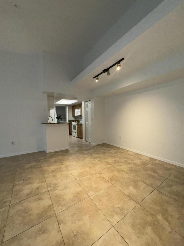 kitchen featuring sink, white appliances, light tile patterned floors, kitchen peninsula, and dark stone counters