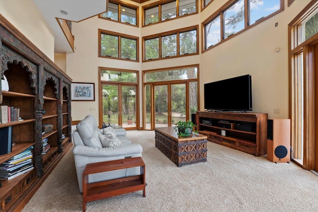 carpeted living room with a wealth of natural light, french doors, and a towering ceiling