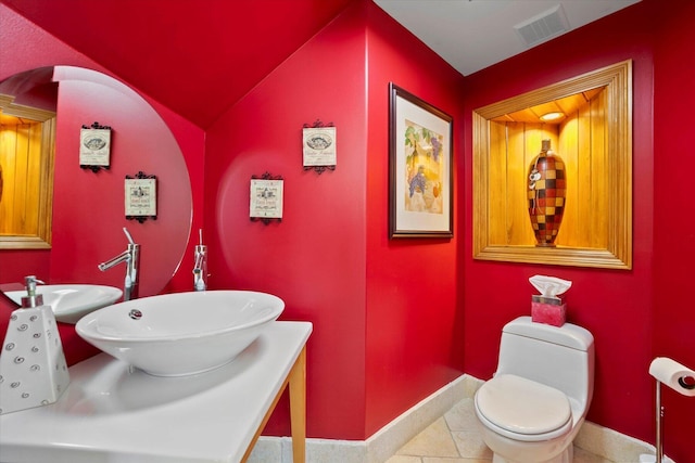 bathroom featuring tile patterned flooring, toilet, sink, and vaulted ceiling