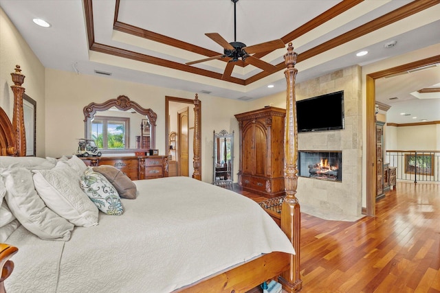 bedroom with ceiling fan, wood-type flooring, crown molding, and a tray ceiling