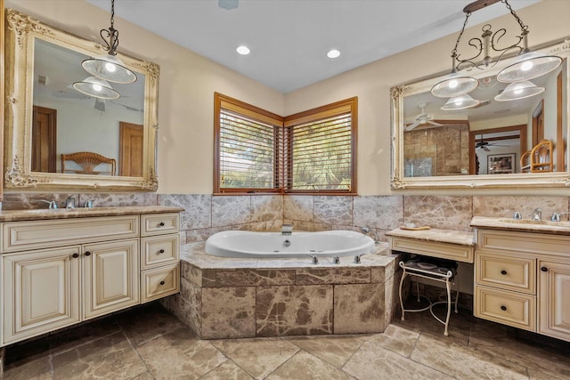 bathroom with vanity, a relaxing tiled tub, and ceiling fan